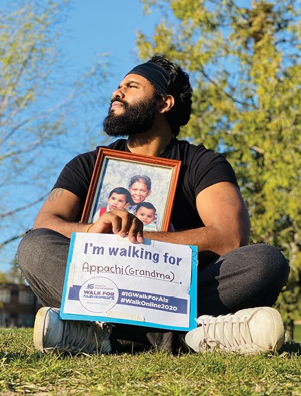 Man at a virtual IG Wealth Management Walk for Alzheimer's holding a sign showing who he is walking for.