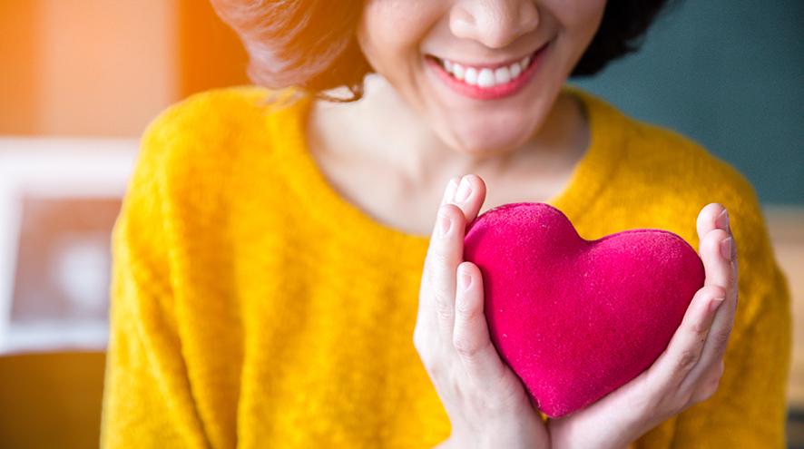 Young woman holding toy heart.